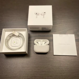 AirPods Pro - 2022 Apple AirPods Pro i mycket fint skick, komplett med originalförpackning, laddningskabel, extra öronkuddar och manual. Trådlösa hörlurar med aktiv brusreducering och laddningsetui. Inga synliga repor eller skador, allt fungerar som det ska. Köpte dem för ungefär 2 år sedan för 2000kr.
