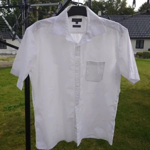 Vit kortärmad skjorta från Atlant - Klassisk vit skjorta från Atlant i storlek M. Skjortan har korta ärmar, bröstficka och knäppning framtill. Snygg och enkel design med bred krage, tillverkad i non iron-bomull som gör den lättskött och bekväm.