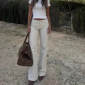 Beige wide byxor med låg midja - Avora ”forte” trousers. Snygga beige byxor med hög midja och wide fit. De har raka ben med lätt utsvängning och är tillverkade i ett mjukt bomullsmaterial. Storlek 34. 