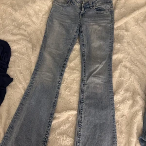 Ljusblå bootcut jeans med fickdetaljer - Snygga ljusblå bootcut jeans från Perfect Jeans med klassisk femficksdesign och coola bakfickor med lock och knapp. Jeansen har en lätt tvättad look och normal passform. Perfekta för dig som gillar en avslappnad men trendig stil.