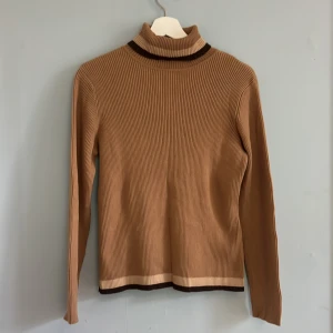 Brun polotröja - Brun polotröja i flera nyanser. Croppad och i 70-tals stil. Tjockt material. Gott skick, inga defekter eller missfärgningar. Storlek M