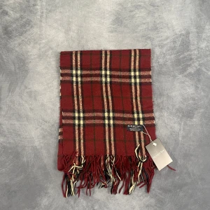 Burberry Halsduk - Skick: 7/10 (Vintage), begagnad, inga defekter. | Vad som ingår: Endast halsduken. | Ordinarie pris: +- 4000 SEK / 400 €. | ​​OBS: Halsdukarna finns i samma färgsättning men kan skilja sig något i modell eller detaljer, beroende på tillverkningsår eller kollektion