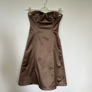 Strapless Mididress Metallbrown - En sleeve-/strapless midiklänning i färg av brun metall. Finns mer utrymme i bysten, skulle tippa att A, B 70-75 i BH storlek passar.