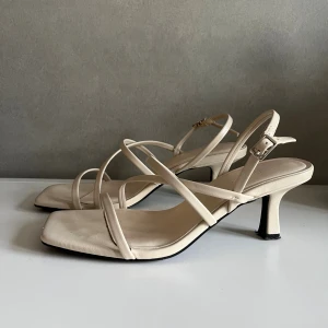 Beige klackskor  - Snygga beige/ vita klackskor med låg klack och justerbart spänne vid ankeln. Skorna är ifrån pullandbear och har använts 2-3 gånger max. Skorna är i fint skick med några skavanker som knappts märks, skriv vid frågor annars är det bara att köpa💕🫶🏼