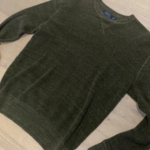 Olivgrön stickad tröja Polo Ralph Lauren -  Passar även s Mysig olivgrön stickad tröja från Polo Ralph Lauren i storlek XS. Tröjan har rund halsringning, diskret broderad logga på bröstet och långa ärmar. Perfekt för lager-på-lager och chill höst- och vinterstil. Mycket fint skick