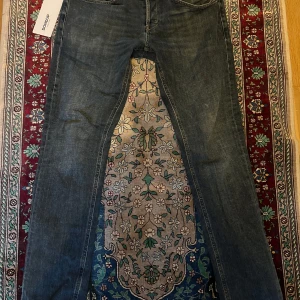 Mörkblå jeans från Dondup - Snygga mörkblå jeans från Dondup med klassisk femficksdesign och subtila slitningar. Jeansen har raka ben och normal passform, tillverkade i mjukt denimtyg som ger en skön känsla. Perfekta för dig som gillar stilrena och tidlösa jeans. Nypris 3100:-, pris kan diskuteras