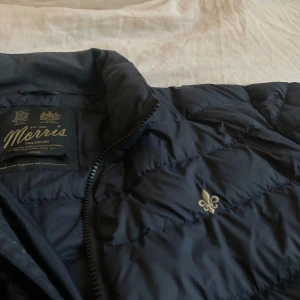 Morris Milford Liner Jacket - Snygg mörkblå dunjacka från Morris i storlek S. Jackan är quiltad med diskret logga på bröstet och dragkedja framtill och i mycket gott skick. Perfekt för kyliga dagar och har en klassisk, stilren look som funkar till det mesta. Inköpt förra vintern (Nypris är 2900kr). Skriv om ni har några frågor eller funderingar! 