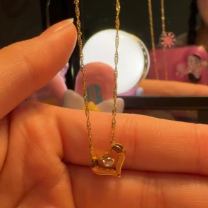 Guldhalsband hjärta med zirkonia Guldfynd - Superfint halsband i 18K guld från Guldfynd med Singaporekedja och ett hjärtformat hänge med en gnistrande kubisk zirkonia i mitten. Kedjan är 42+3 cm lång och hänget är ca 11 mm brett. Perfekt för dig som gillar eleganta och söta smycken. 