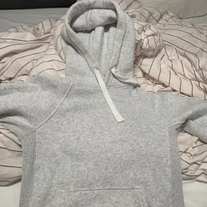 Grå hoodie från Ruess merch XS - Ljusgrå hoodie från ruessmerch i storlek XS. Klassisk modell med huva och snörning, samt magficka framtill. Mjuk och skön, perfekt för chill dagar. Ruess logga tryckt på ärmen för en extra touch. Helt sprillans ny utan lapp jag gillar bara inte hur den sitter på mig