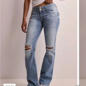 Ljusblå bootcut jeans med slitningar - Snygga ljusblå jeans med bootcut passform och slitna detaljer vid knäna. Jeansen har klassiska fem fickor, dubbla knappar i midjan och coola ficklock bak. Perfekta för dig som gillar en avslappnad men trendig look. Priset kan diskuteras 