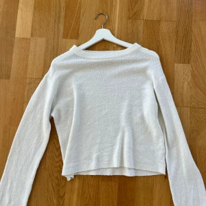 Vit stickad tröja med lång ärm - Mysig vit stickad tröja med lång ärm och avslappnad passform. Tröjan har en enkel design med ribbade kanter vid hals, ärmslut och nederkant. Perfekt för lager-på-lager och chill dagar.