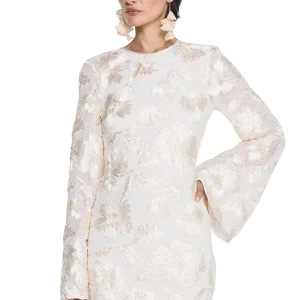 Vit blommig kortklänning med trumpetärm - Superfin vit kortklänning med blommigt mönster i champagnefärg. Klänningen har långa trumpetärmar, rund halsringning och snygg knytning i ryggen. Materialet är glansigt och känns lyxigt, med dragkedja i sidan för enkel påklädning. Perfekt för studenten & mottagningen klänningen är speciellt utformad för att passa studentdagen och mottagningen.