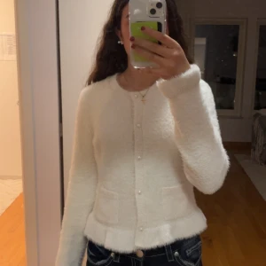 Vit fluffig kofta från Lindex - Supermjuk och söt fluffig vit kofta från Lindex med pärlknappar och två små fickor framtill. Den är snygg att ha över en tröja eller försig!💞