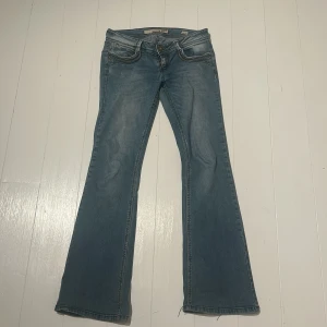 Blå bootcut jeans från Sissy Boy - Snygga blå bootcut jeans från Sissy Boy med broderade detaljer och diamanter på bakfickorna. Jeansen har klassisk femficksdesign, låg midja. Dragkedjan är söder men går fortfarande att dra upp bara att den åker ner igen. Även lite slitna längst ner (kom privat för bild på det). Har även tappad nån liten sten/berlock på lappen där bak som man kan se om man zoomar in💕innerbens längd=81cm midja (rakt över)=37cm. Längd på hela jeansen= 101cm. Osäker om det är S eller M💕