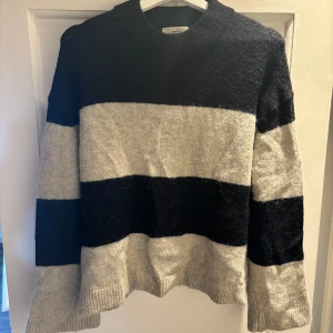 Randig stickad tröja från Gina Tricot - Säljer en stickad tröja från Gina Tricot i storlek XS. Tröjan har breda svarta och gråa ränder, rund halsringning och långa ärmar. 