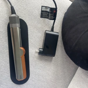 Dyson Corrale - Dyson Corrale plattång i koppar/svart med original laddare och bas. Synligt i mycket gott skick, inga tydliga repor eller slitage. Trådlös design med flexibla plattor för skonsam styling och flera värmeinställningar. Perfekt för både lockar och rakt hår.