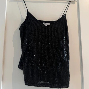 Svart paljettlinne från Bubbleroom - Supersnygg svart linne-topp från Bubbleroom med tunna axelband och täckt av glittrande paljetter. Ny med prislapp på storlek S