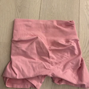 Rosa seamless shorts från Aim'n - Säljer ett par ljusrosa seamless shorts från Aim'n med hög midja och ribbad linning. De är stretchiga och sitter tajt, perfekta för träning eller chill. Materialet är mjukt och följsamt, och shortsen har en enkel, stilren design utan mönster eller extra detaljer.