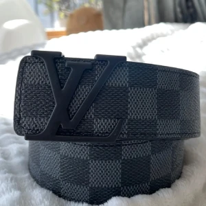  rutigt svart bälte - Snyggt  med klassiskt svart och rutigt mönster i svart och grått. Bältet är gjort i skinn med en stilren design och bred passform. Perfekt accessoar för att lyfta din outfit med en exklusiv touch.