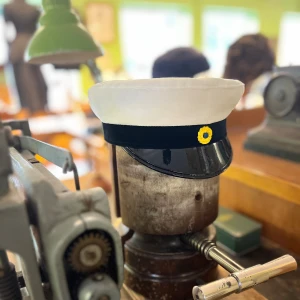 Klassisk studentmössa (Uppsala) 52-63 - Klassisk studentmössa med vit ovandel i bomull, svart band och blank svart skärm. Framtill sitter en klassisk kokard. Insidan har det klassiska foder i blått och gult. Finns storlekar från 52 – 63. Fråga oss innan du beställer. (Limiterat lager)