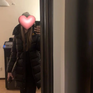 Svart lång pufferjacka med huva - Säljer en svart lång pufferjacka från parajumpers köpt från kidsbrandstore med stor huva och quiltad design. Jackan har dragkedja framtill och en snygg, stilren look som passar perfekt när det är kallt ute. Den är vadderad och har en klassisk pufferstil som håller dig varm hela vintern. Endast använd en halv vinter (förra vintern), nypris 5600. 