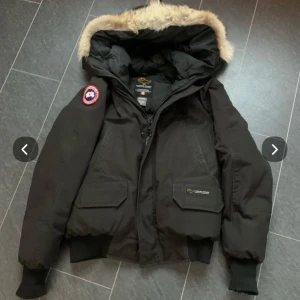 Svart dunjacka från Canada Goose -  Svart vinterjacka från Canada Goose. Har tagit av pälsen på luvan, därav priset. Pälsen följer med om man vill sy på den igen. Jackan är äkta och en gammal herrmodell från 90-talet. 