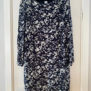 Svart och grå mönstrad kortklänning - Snygg svart och grå kortklänning med mönster och trekvartsärm. Klänningen har en rund halsringning och en liten knappdetalj i nacken. Materialet känns lätt och luftigt, perfekt för dig som gillar en chill och stilren look. Mått Över bröstet: ca 50 cm Över höften: ca 48 cm Total längd från axeln och ner: ca 95 cm  Klänningen: 100% viskos Underklänningen: 100% polyester   Kommer från ett djur och rökfritt hem.