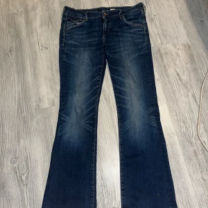 Levis bootcut jeans mörkblå - Mörkblå lågmidjade jeans från Levis med klassisk bootcut passform. Snygga slitningar framtill och bakfickor med knappstängning. Jeansen har fem fickor och är tillverkade i robust denim med en skön känsla. Perfekt för dig som gillar en tidlös och cool stil.