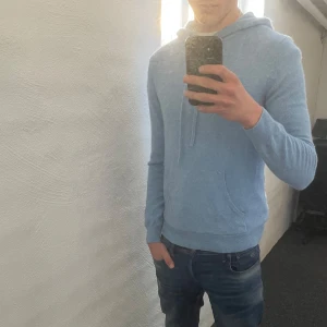 Ljusblå kashmir hoodie - Säljer en supermjuk ljusblå tröja i 100% kashmir. Den har en klassisk design med dragsko i huvan och en praktisk magficka. Tröjan passar storlek S men även M då jag är 189 cm. Hör av er vid funderingar!