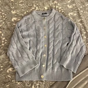 Kabelstickad kofta - Ljusblå kabelstickad kofta från Gina. Liten sminkfläck på insidan av halsen (se sista bilden) men det syns knappast. Kolla gärna in mina andra annonser, vill du köpa flera varor så kommer vi överens om ett bra paketpris och så sparar du på frakten med💗