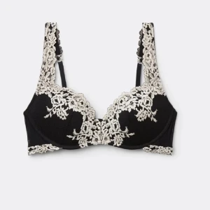 Svart spets-bh med blommig brodyr - Snygg svart bh med vit blommig spets och broderade detaljer längs kupor och axelband. Ger en lyxig och feminin känsla med sina kontrasterande färger och eleganta spetsmönster. Perfekt för dig som gillar stilrena och romantiska underkläder.