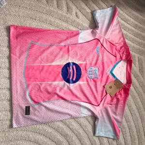 Rosa FC Barcelona x Spotify matchtröja - Säljer en riktigt snygg FC Barcelona fotbollströja från Nike i rosa och ljusblått med Spotify-logga på bröstet. Tröjan har korta ärmar, klubbmärke och Nike swoosh framtill. Tillverkad i lätt och ventilerande material, perfekt för match eller träning.