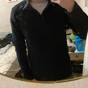 Svart manchester skjorta från H&M - Svart skjorta från H&M i slim fit med snygg krage och knappar framtill. Tillverkad i mjuk manchester som ger en cool och modern känsla. Långärmad modell som passar perfekt till jeans eller chinos. Perfekt för dig som gillar stilrena och enkla plagg. Sitter perfekt på dig runt 178-180cm! Klockren att ha när något ska firas! 