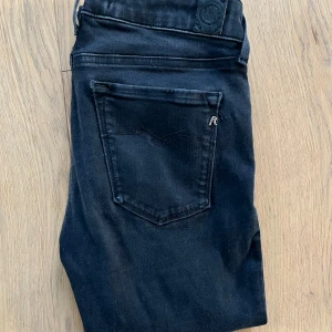 Svarta Replay Hyperflex jeans - Svarta Replay Hyperflex jeans i modellen New Luz. Jeansen har en klassisk femficksdesign, silverfärgade detaljer och stretchigt material för extra komfort. Snygg passform med smal siluett och diskret Replay-logga på bakfickan.