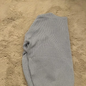 Ljusblå stickad tröja från Sinsay XS - Supermysig ljusgrå stickad tröja från Sinsay i storlek XS. Tröjan har v-ringning, långa ärmar och ribbade muddar vid ärmslut och nederkant. Perfekt för lager-på-lager och chill dagar.