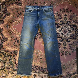 Replay blå jeans straight fit Thad 16Y 166 - Säljer ett par klassiska blå jeans från Replay med straight fit och normal passform. Jeansen har fem fickor, snygga slitningar och Replay-logga på bakfickan. Materialet är slitstarkt denim och färgen är mellanblå med ljusare tvättade partier. Midja 37cm längd 93cm (34)