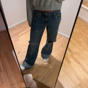  blå  jeans med slitningar - Säljer ett par blå jeans med rak passform och slitna detaljer vid knäna. Perfekta för dig som gillar en avslappnad och trendig look. Aldrig använda och pris kan alltid diskuteras!