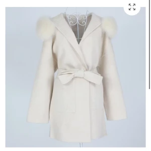 Feminina of Sweden Kappa - Säljer en beige kappa från Femmenina of Sweden med fluffiga pälsdetaljer på axlarna och ett snyggt bälte i midjan. Jackan har en omlott-design, stora fickor och lång ärm. Perfekt för dig som gillar en chic och trendig look. Kappan är varsamt använd. Kappan är i storlek xs men passar både M och S. Typ one size storlek alltså. Nypris 3699kr, säljer då den inte kom till användning. OBS! Äkta pälskrage🌸 (Inta mina bilder, bilderna är direkt från feminina men bild på kappan kan skickas om det önskas)