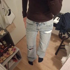 Ljusblåa wide jeans med slitningar - Säljer ett par ljusblå jeans med bred passform och snygga slitningar på låret och knät. Jeansen har klassisk femficksdesign och hög midja. Perfekta för dig som gillar en avslappnad och trendig stil. Säljer dem pga att dem inte kommer till användning, använt dem 3 gånger och nypris är 1200 kr. Jag säljer dessa edikted jeans för 800 men pris kan pratas❤️