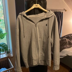 Grå hoodie från Polo Ralph Lauren - Säljer en stilren grå hoodie från Polo Ralph Lauren med dragkedja och huva. Den är storlek M men passar S också, skriv om ni undrar något så skall jag försöka svara så snabbt jag kan