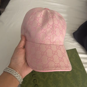 Rosa keps  GG-mönster - Säljer en snygg rosa keps med ikoniskt GG-mönster över hela kepsen. Kepsen har justerbart spänne bak i rosa läder och är tillverkad i ett stilstarkt mönster. Box tillkommer