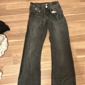 Grå bootcut jeans från Gina Tricot - Snygga grå jeans från Gina Tricot i storlek 158. Modellen har bootcut-ben, klassiska fem fickor och dubbla knappar i midjan. Jeansen har ljusa slitningar och kontrastsömmar som ger en cool vibe. Perfekta för dig som gillar en avslappnad stil.