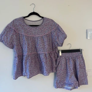 Ljuslila blommig pyjamas sett - Säljer ett pyjamas sett med små blommor i rosa och lila. De har en loose passform. Materialet är mjuk bomull, perfekt för varma dagar. Matcha med en oversized t-shirt eller hoodie för en chill look.