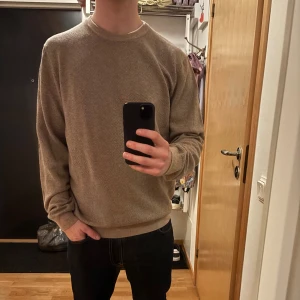 Beige stickad tröja Hansen & Jacob - Snygg beige stickad tröja från Hansen & Jacob i merinoull och bomullsblandning. Crew neck och diskret fiskbensmönster ger en clean och modern look. Perfekt för dig som gillar stilrena och bekväma plagg med lite extra känsla. Nypris ligger på 2000