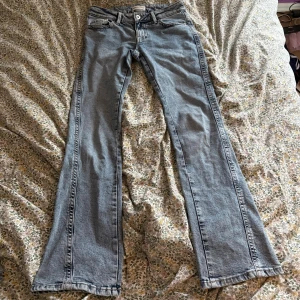 Low waist bootcut  jeans  - Snygga ljusblå bootcut jeans från Gina Tricot storlek 34. Klassisk femficksmodell med broderade detaljer på bakfickorna och knappstängning fram. Jeansen har en rak passform upptill och utsvängda ben, vilket ger en cool siluett.