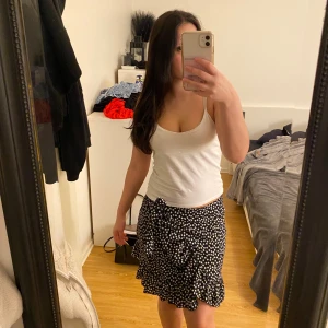 Svart blommig omlottkjol från SHEIN - Supersöt svart omlottkjol från SHEIN med vita små blommor och volangkant. Kjolen har knyt i sidan och sitter snyggt i midjan. Perfekt för dig som gillar en feminin och trendig stil.