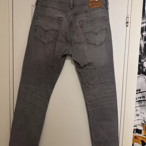 Levi's 502 grå jeans W34 L32 - Snygga grå jeans från Levi's modell 502 med klassisk femficksdesign och läderpatch bak. Jeansen har rak passform och normal midja, tillverkade i slitstarkt denim. Perfekt för dig som gillar en stilren look med lite edge.knappt använda, nypris 1000kr