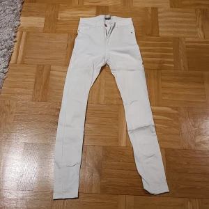 Vita Molly jeans XS från Perfect Jeans - Säljer ett par vita Molly jeans från Perfect Jeans i storlek XS. Modellen är skinny med hög midja och klassisk femficksdesign. Byxorna har dragkedja och knapp framtill, och är gjorda i mjukt bomullsmaterial med stretch för skön passform.