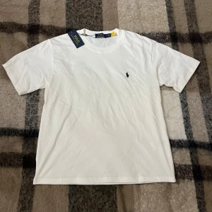 Polo Ralph Lauren T-shirt - Klassisk vit t-shirt från Polo Ralph Lauren i mjuk bomull. För bra pris👍T-shirten är i storlek S (relaxed fit) medföljer också med tags 🏷️. Scan funkar✅ inga defekter & inga fläckar😌 Perfekt som present eller eget köpt🙌 Kontrakta vid intresse🤝