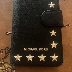 Nytt Mobilfodral Michael Kors iPhone 7 - Nytt Folio mobilfodral av Michael Kors. Tillverkat av Saffiano läder. Det är magnetisk stängning och fack på insidan för kort & kontanter. Måtten är:Höjd 138,3mm Bredd:67,1mm Djup:7,1mm. Nu kan ni se vilka mobiler förutom iPhone som passar. Detta fodral tillverkas inte längre så passa på att köpa det. 